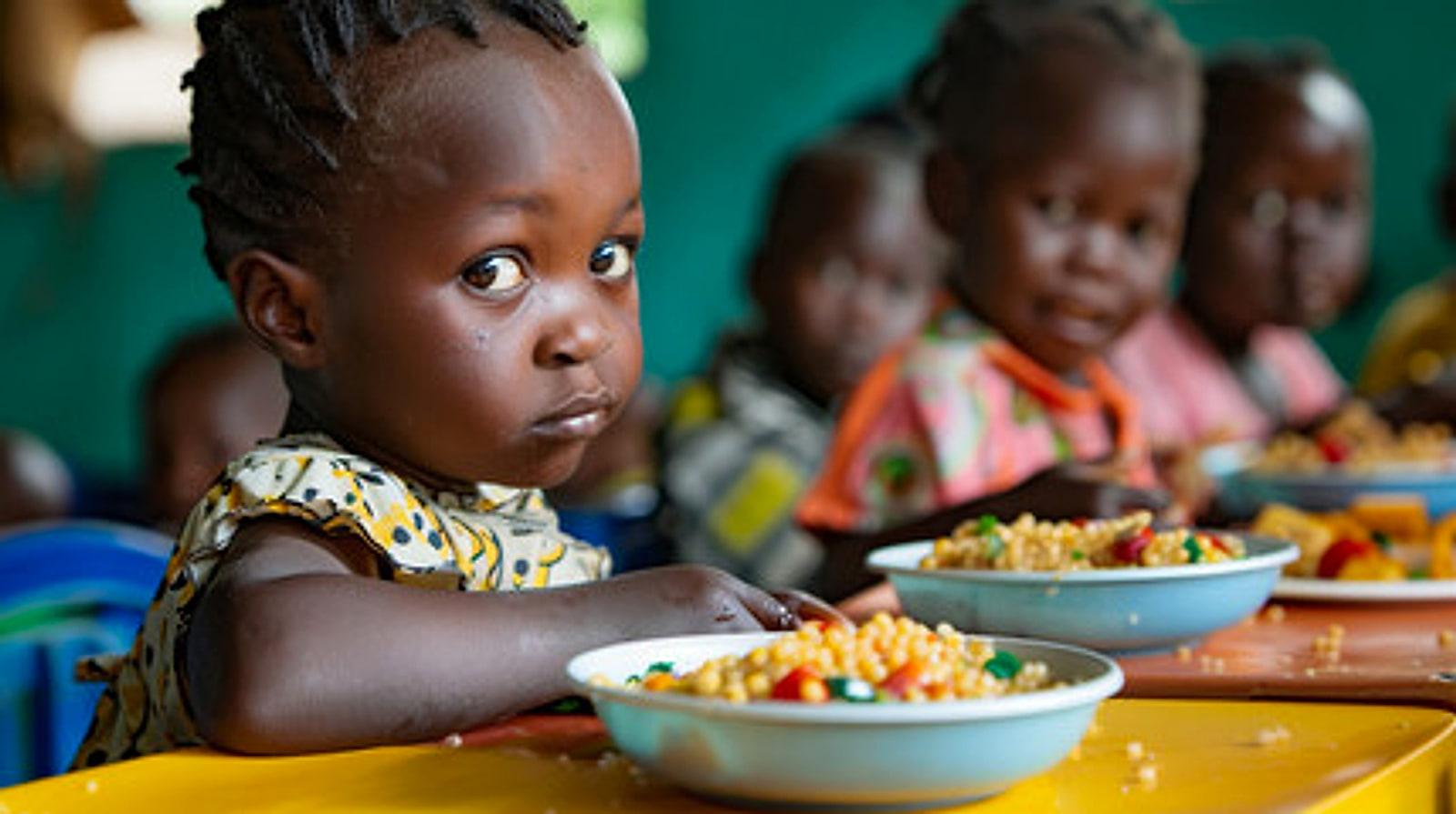 Young children seated at a table with bowls of food